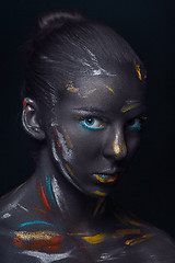 Image showing Portrait of a young woman who is posing covered with  black paint 