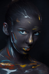 Image showing Portrait of a young woman who is posing covered with  black paint 