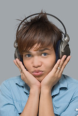 Image showing Teen with headphones holding his head