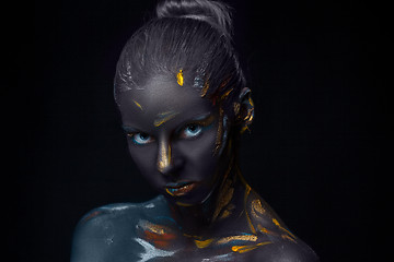 Image showing Portrait of a young woman who is posing covered with  black paint 