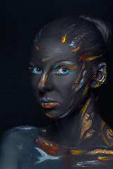 Image showing Portrait of a young woman who is posing covered with  black paint 