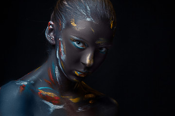 Image showing Portrait of a young woman who is posing covered with  black paint 