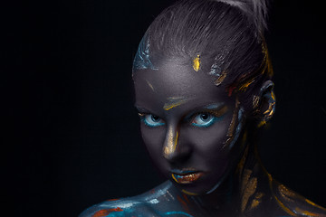 Image showing Portrait of a young woman who is posing covered with  black paint 