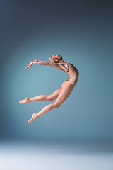 Image showing Young beautiful modern style dancer jumping on a studio background