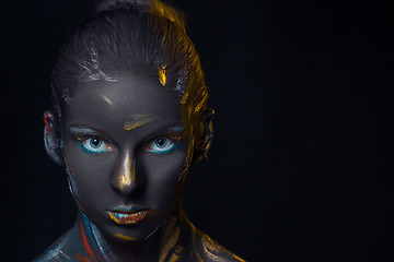 Image showing Portrait of a young woman who is posing covered with  black paint 