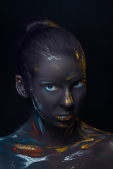 Image showing Portrait of a young woman who is posing covered with  black paint 