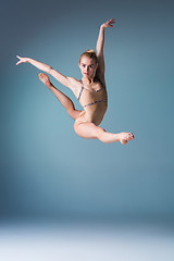 Image showing Young beautiful modern style dancer jumping on a studio background