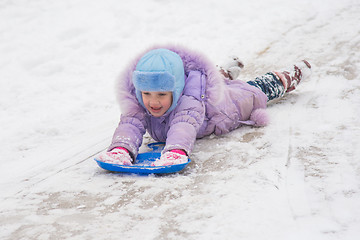 Image showing Girl is rolling on his stomach with a headfirst slide snow