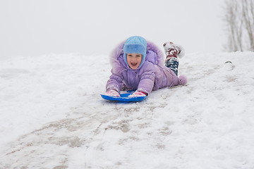 Image showing Girl rolls down on his stomach with a headfirst slide snow