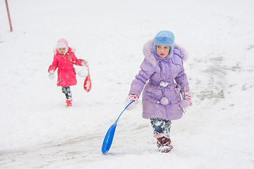 Image showing Two girls climb up the icy hill