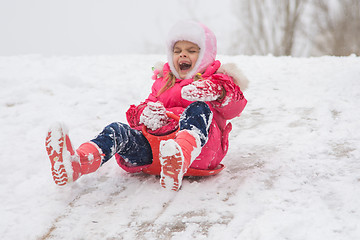 Image showing A girl screaming and shrieking ice slides down hill