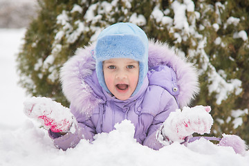 Image showing Girl lying in the snow the snow with snowballs in hand