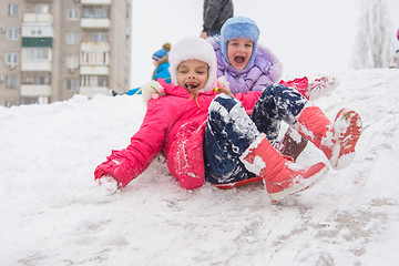 Image showing Two happy girls slide down the icy hill