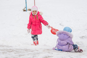 Image showing Girl goes up the hill, the other girl rolls down