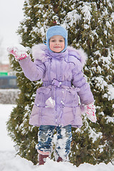 Image showing Girl standing on a snowbank snow with snowball in hand