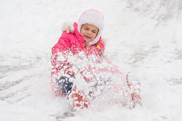 Image showing Girl rolls down a hill of snow closed her eyes came off the boots
