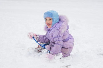 Image showing Happy little girl slid down the icy hill and happily watching the other children