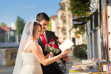 Image showing Beautiful wedding couple reviewing vintage books.