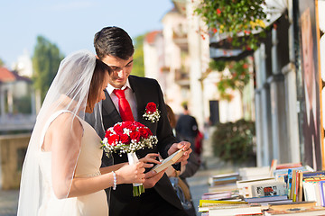 Image showing Beautiful wedding couple reviewing vintage books.