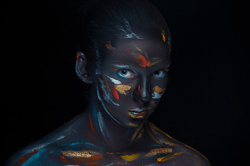 Image showing Portrait of a young woman who is posing covered with  black paint 