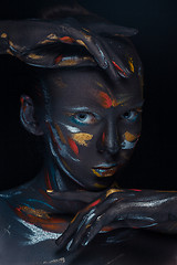 Image showing Portrait of a young woman who is posing covered with  black paint 