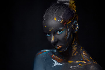 Image showing Portrait of a young woman who is posing covered with  black paint 