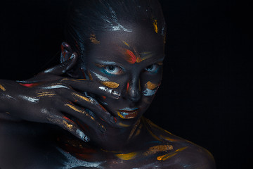 Image showing Portrait of a young woman who is posing covered with  black paint 