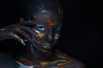 Image showing Portrait of a young woman who is posing covered with  black paint 