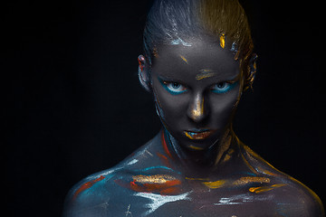 Image showing Portrait of a young woman who is posing covered with  black paint 