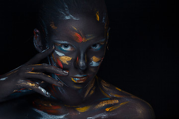 Image showing Portrait of a young woman who is posing covered with  black paint 