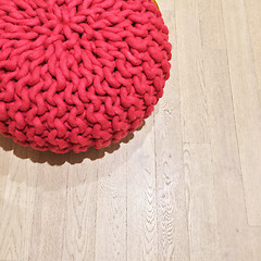 Image showing Woven red pouf on wooden floor