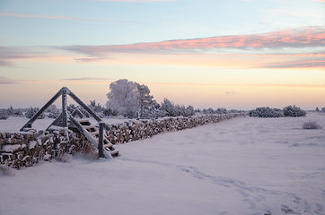 Image showing Dawn at a winterland with a stile by stone wall