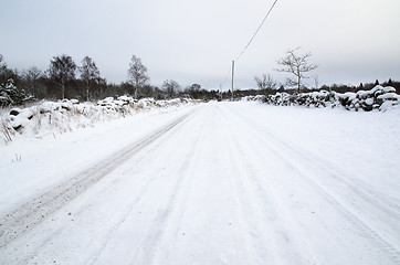 Image showing Snowy road surrounded of stone walls