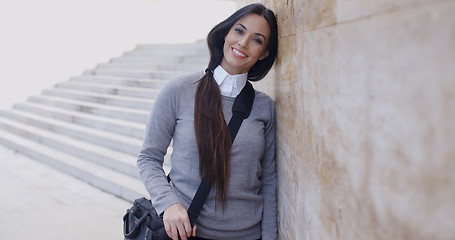 Image showing Grinning woman in sweater near wall looking over
