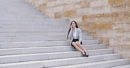 Image showing Happy executive with phone and seated on stairs