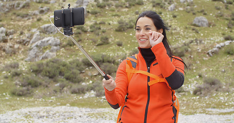 Image showing Smiling young backpacker using a selfie stick