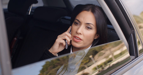 Image showing Serious female executive on phone in limousine