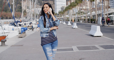 Image showing Young woman chatting on her phone in the street