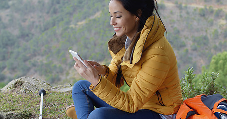 Image showing Smiling female hiker using her phone