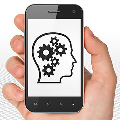 Image showing Finance concept: Hand Holding Smartphone with Head With Gears on display