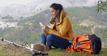 Image showing Smiling female hiker using her phone