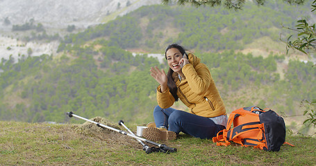 Image showing Happy backpacker on phone and waving hand