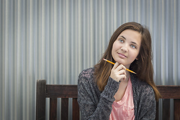 Image showing Young Daydreaming Female Student With Pencil Looking to the Side