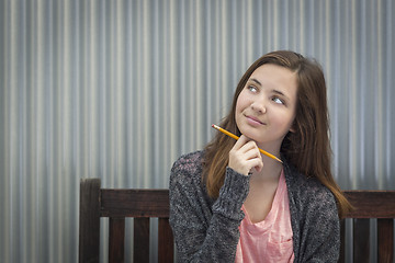 Image showing Young Daydreaming Female Student With Pencil Looking to the Side