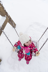 Image showing little girl at snowy winter day swing in park