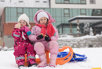 Image showing portrait of two little grils sitting together on sledges