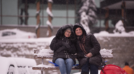 Image showing portrait of two mature woman sitting in park at  winter day