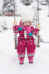 Image showing little girl at snowy winter day swing in park