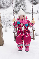 Image showing little girl at snowy winter day swing in park