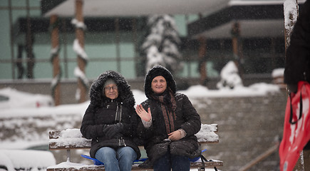 Image showing portrait of two mature woman sitting in park at  winter day